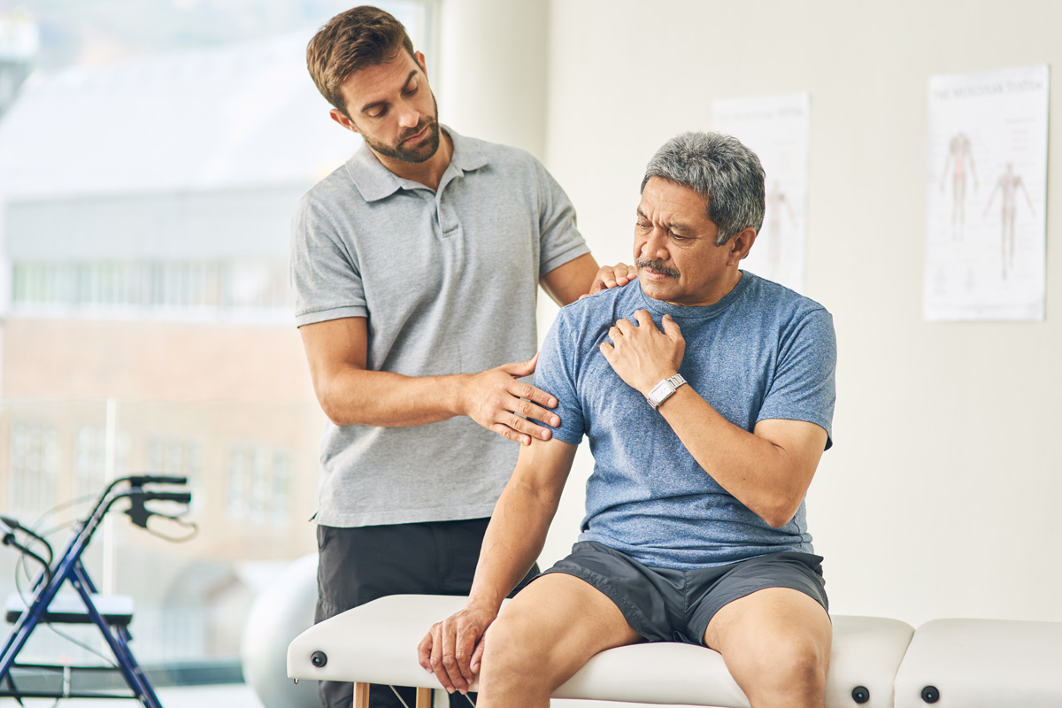 A physical therapist examining a man’s shoulder in Bethesda.