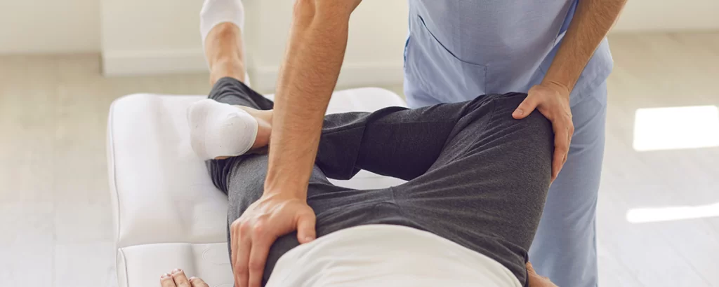 Hands of professional man chiropractor manual therapist fixing man patients pelvic bones