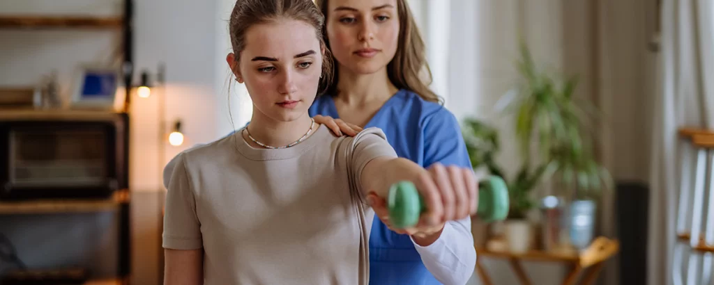 Teenage girl doing exercise with therapist